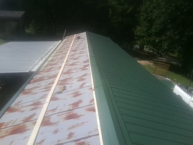 Old rusted panels beside newly installed green metal roofing — Wind Damage Roof Repair by Roofing Brothers in Lakeside