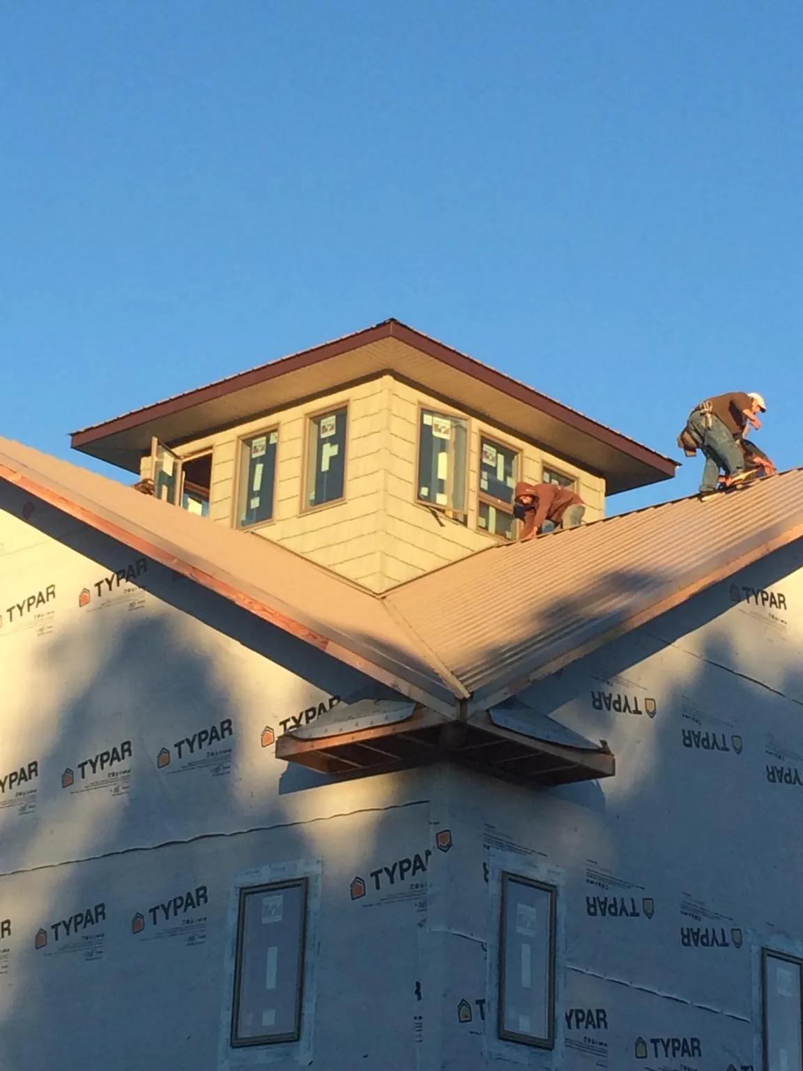 Roofers working around a rooftop cupola on a new metal roof at sunset — Roof Waterproofing in Lakeside by Roofing Brothers
